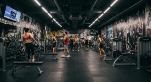 a dynamic interior shot of a vibrant gym bustling with energetic fitness enthusiasts, featuring state-of-the-art equipment and motivational wall art, showcasing the lively atmosphere of sweat 60 in santa monica.