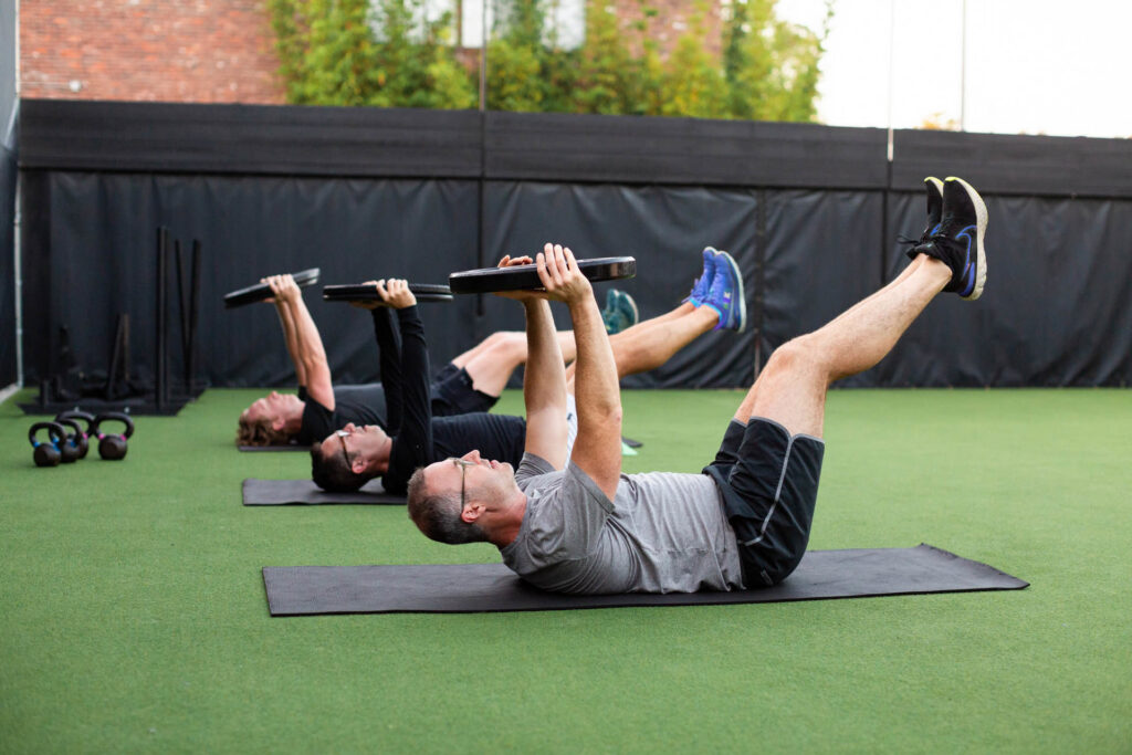 small group of athletes training together with a coach in a well-equipped fitness studio