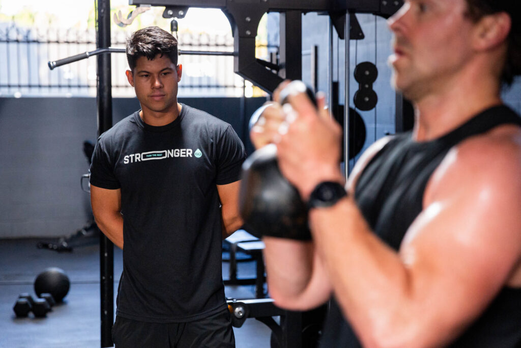 A coach guiding a small group through a strength training session in a modern fitness studio