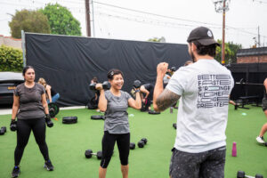 : small group of adults performing strength training exercises together in a bright, well-equipped fitness studio